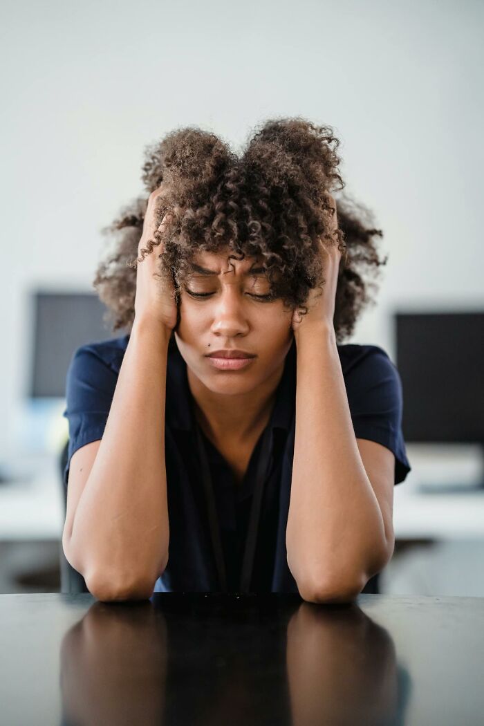 Young woman with curly hair holding her head, reflecting on moments of intuition being proved right.