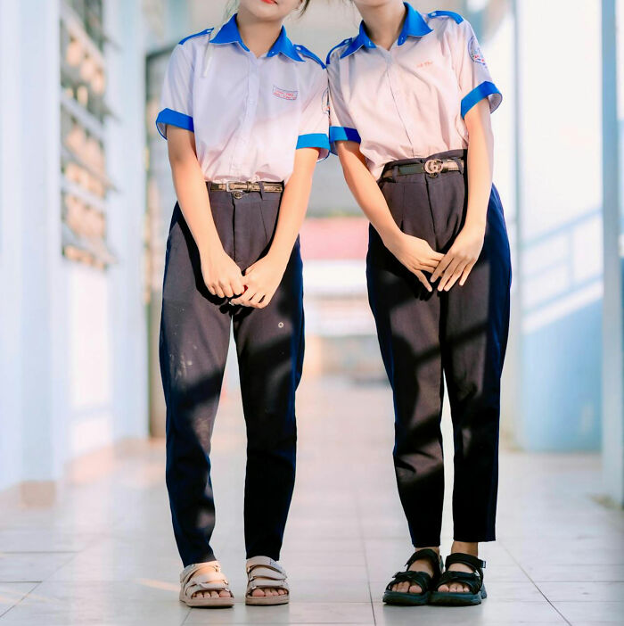 Two young women standing side by side wearing matching school uniforms, illustrating stories about moms.