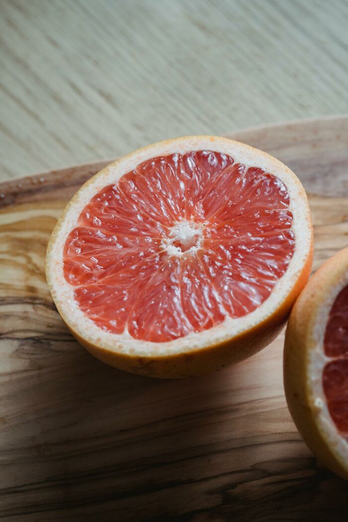 Close-up of a halved grapefruit on a wooden surface illustrating weird and interesting medical facts about nutrition.