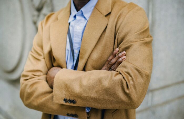 Person wearing a tan coat and blue shirt with arms crossed, symbolizing intuition being proved right in real life situations.