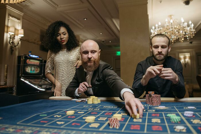 A diverse group of people playing roulette in a casino. The image evokes interesting rumours.