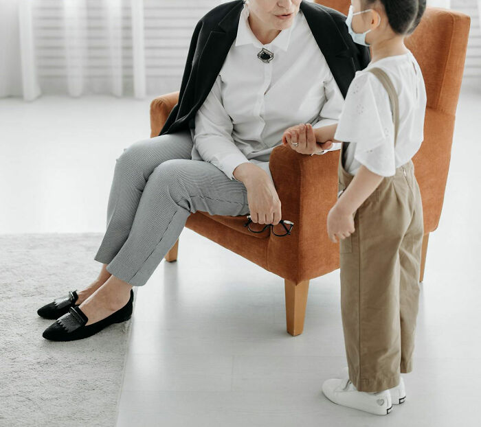 Woman holding a child's hand while sitting in a chair, illustrating touching moments shared by moms and children.