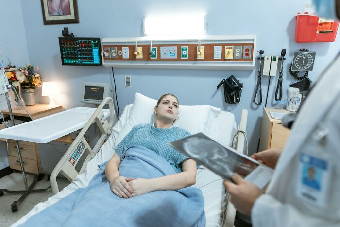 Patient in hospital bed consulting doctor, discovering random facts about their body during a medical visit.