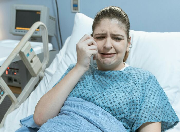 A distressed patient cries in a hospital bed, expressing the emotional impact of disturbing sounds.