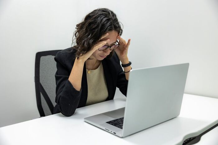 Stressed employee holding head while working on laptop, illustrating wild times employees deciding to quit their job immediately.