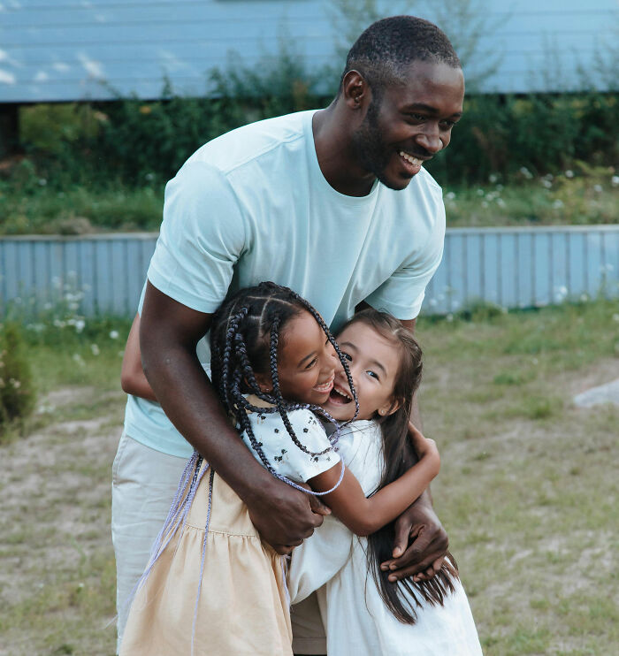 Man and children smiling and hugging outdoors depicting strong bonds and best friends committed moments together.