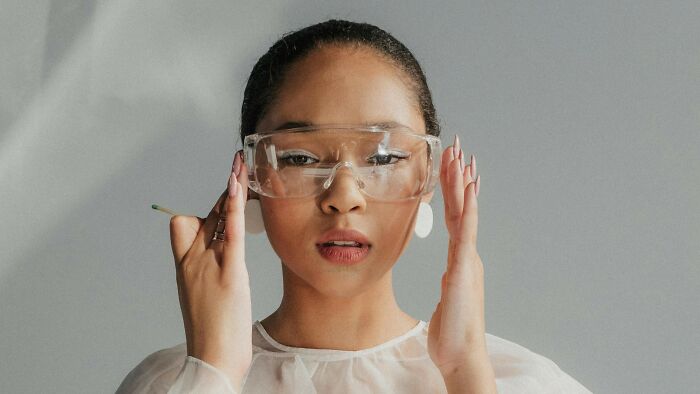 Young woman wearing protective glasses, preparing to answer science questions to test knowledge and understanding.