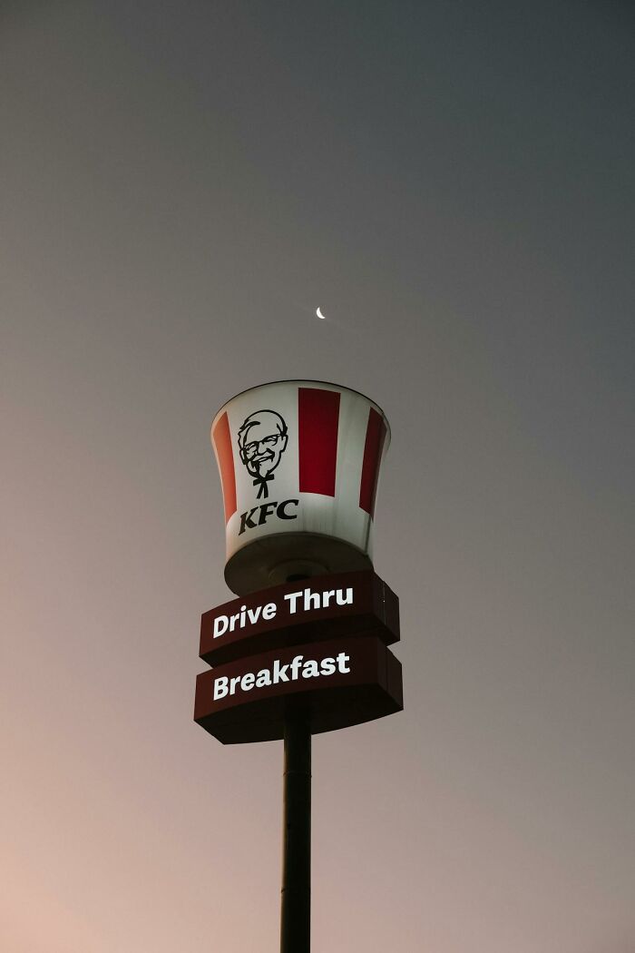KFC drive thru sign with a bucket logo at dusk, illustrating a notable PR mistake by a major company.