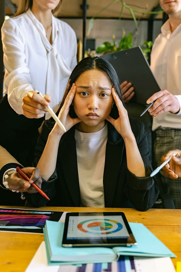 Stressed employee overwhelmed by coworkers demanding attention in an office, reflecting wild times employees quitting immediately.