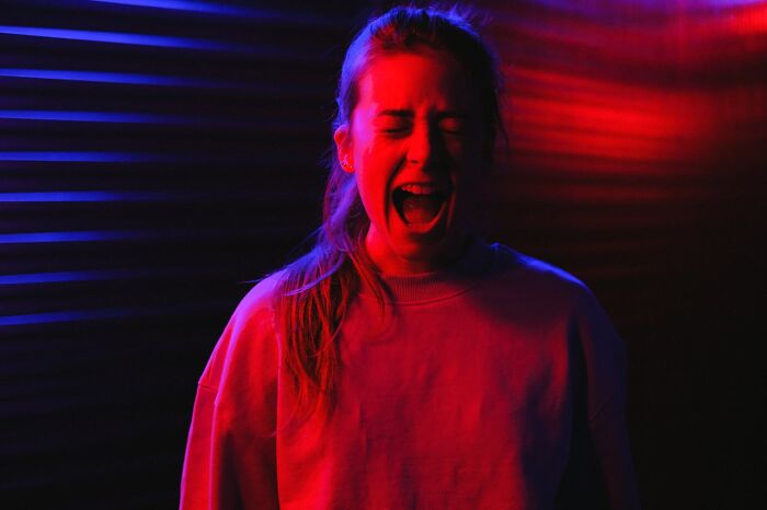 Young woman expressing strong emotion under red and blue lighting, illustrating stories of intuition being proved right.