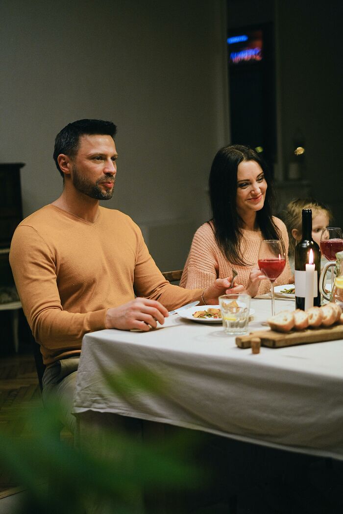 A family enjoys dinner together, with a man and woman smiling at the table. Could family secrets be revealed?
