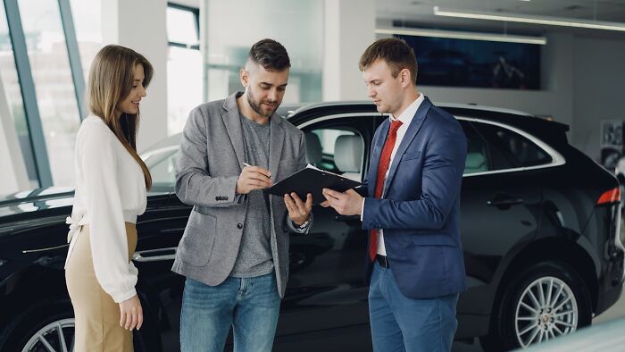 Three people discussing a contract near a car, illustrating stories about people seeing their intuition proved right.