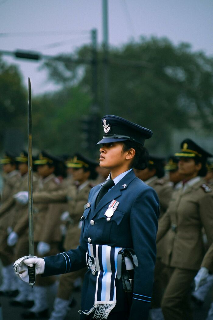 Woman officer in uniform holding a sword during a ceremonial parade, representing strength and stories about moms.