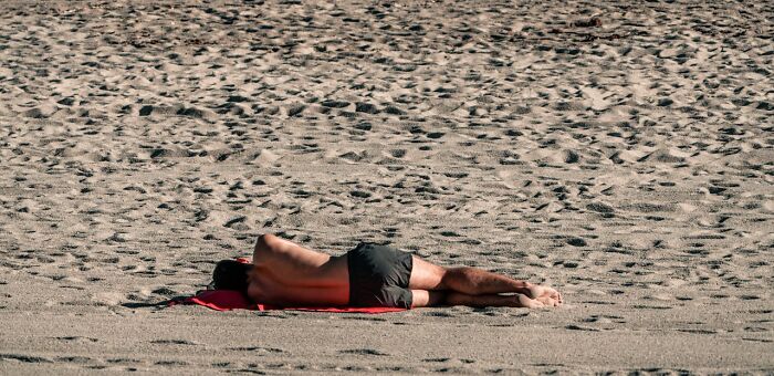 Man lying face down on sand at the beach illustrating unexpected and bizarre ways people passed away.