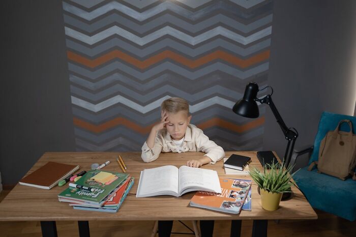Young boy looking tired and stressed while studying at a desk, illustrating terrifying statistics causing sleep trouble.