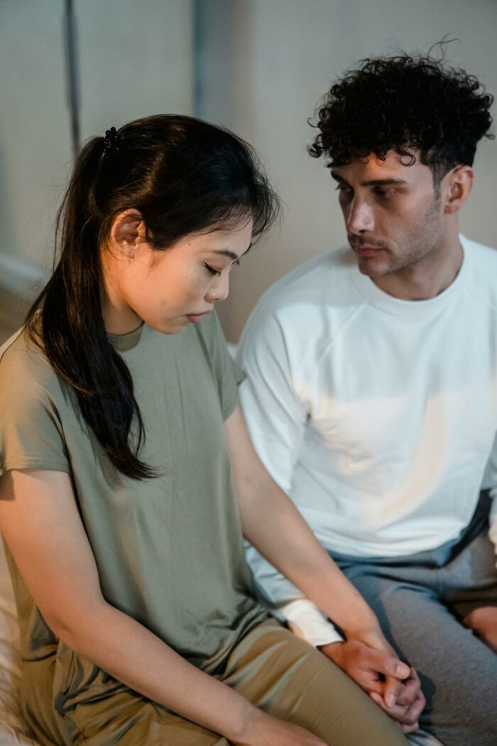 A man and a woman holding hands, both looking somber, reflecting the complexities of divorces.