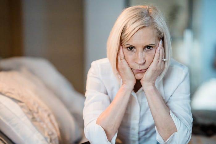 Mulher enfrenta um dilema enquanto sua mãe controla o sono com sua futura esposa, parecendo preocupada e contemplativa dentro de casa.