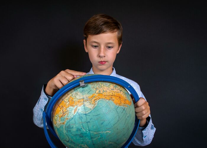 Young boy studying a globe focused on countries people always confuse to prove geography skills in a challenge. Young boy studying a globe focused on countries people always confuse to prove geography skills in a challenge.