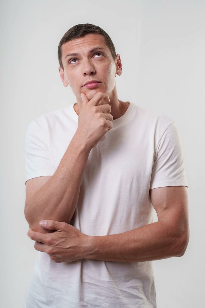 Man in a white shirt pondering with hand on chin, illustrating curiosity about weird and interesting medical facts.