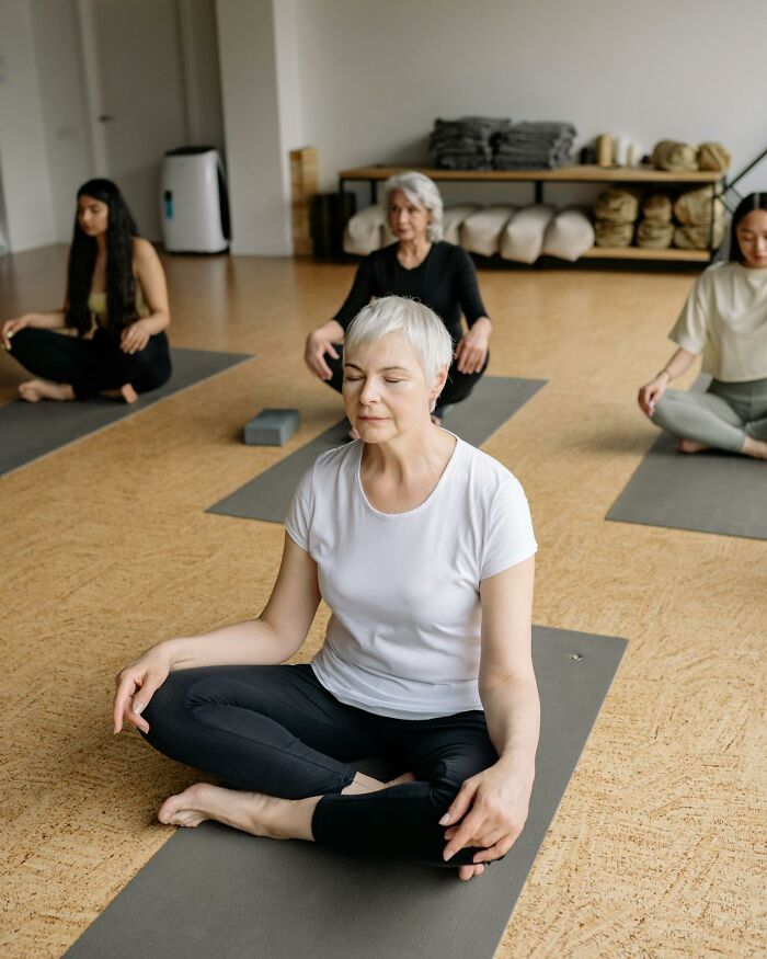 Group of women practicing yoga and meditation indoors, highlighting relaxed and mindful moments with moms.