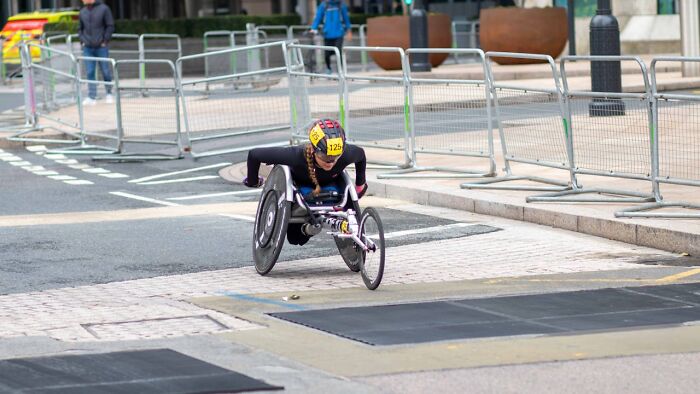 Athlete competing in a wheelchair race on city streets, showcasing strength and determination in an inspiring moment.