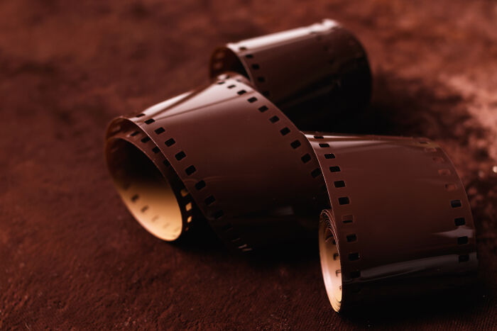 A roll of brown film, unspooled on a dark brown surface, symbolizing people accidentally finding out they were being cheated on.