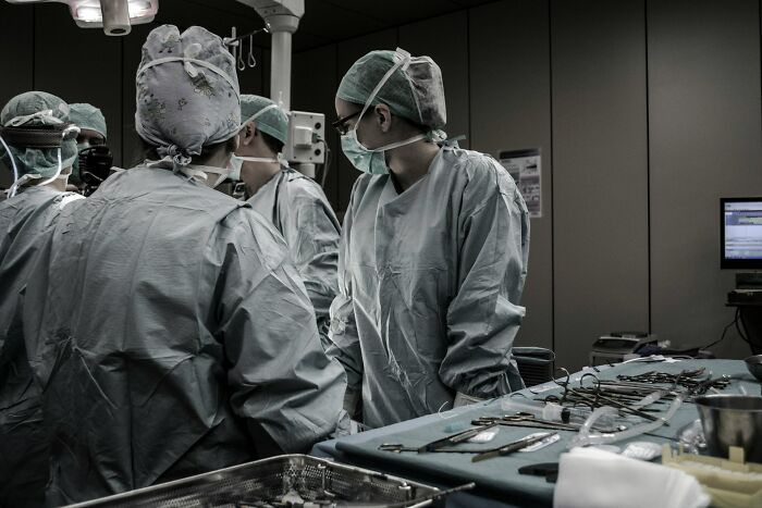 Gynecologists in surgical scrubs and masks discussing during a complex medical procedure in an operating room.