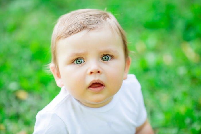Um bebê inocente com grandes olhos azuis e cabelos claros, vestindo uma camisa branca, simboliza o teste de DNA e desvendando um segredo obscuro.