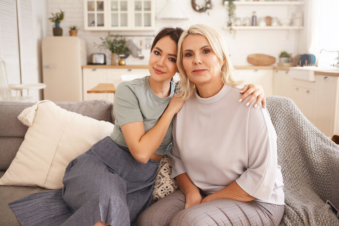 Two women sitting close on a couch sharing an emotional moment after a psychic session with an unexplainable story.
