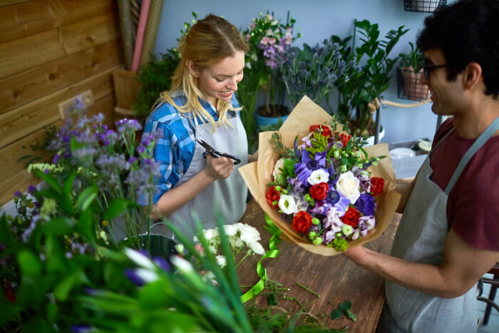 Two florists arranging colorful flower bouquet in shop, an unexpected moment like a story from a psychic session.