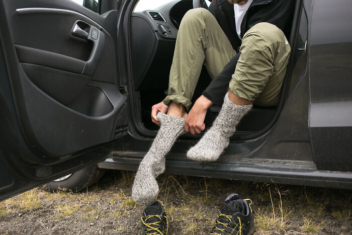 Person putting on thick wool socks while sitting in a car, illustrating unexpected moments from psychic session stories.