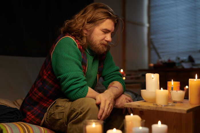 Man in a green sweater at a psychic session surrounded by burning candles, experiencing a mysterious moment.