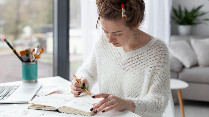 Young woman in a cozy room sketching in a notebook during a psychic session with a story she can’t explain.