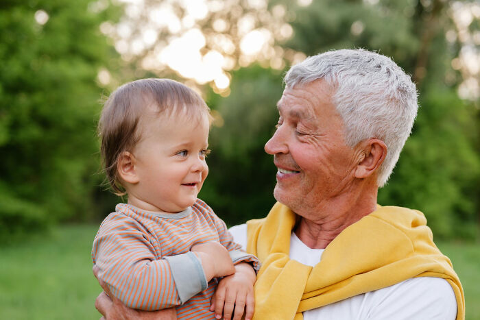Elderly man and toddler smiling outdoors, capturing a heartwarming moment like stories from a psychic session experience.