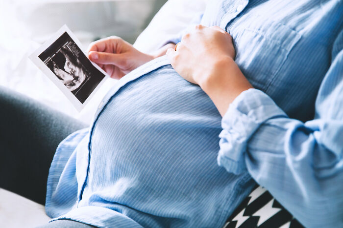 Pregnant woman holding an ultrasound photo during a psychic session with a story she still can’t explain.