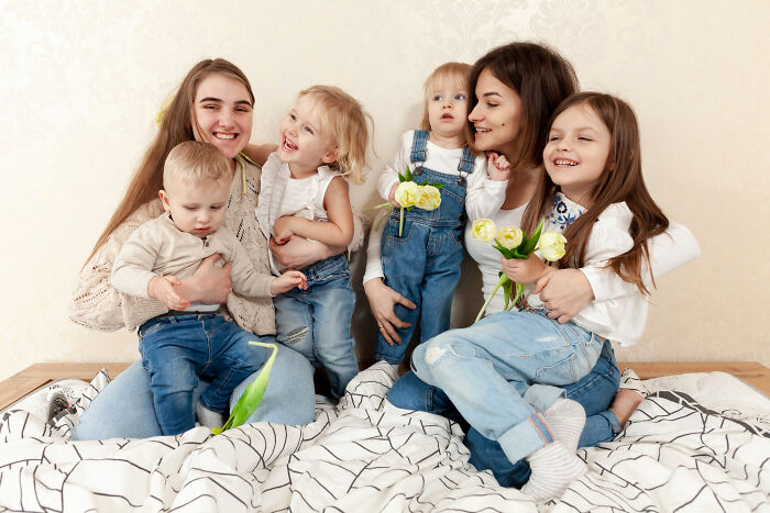 Two women and four children smiling together indoors, capturing a joyful moment at a psychic session.