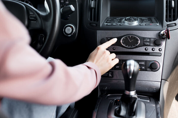 Person adjusting car radio controls while inside the vehicle during a moment connected to psychic session stories.