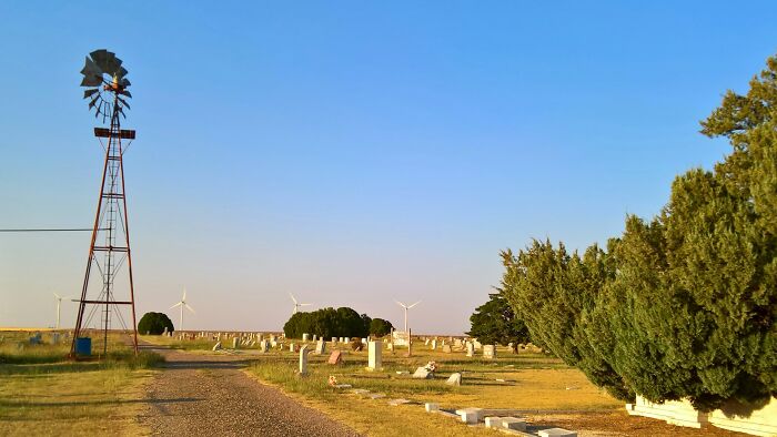 Rural cemetery with windmill and trees under clear blue sky, illustrating tips and tricks parents share outdoors.