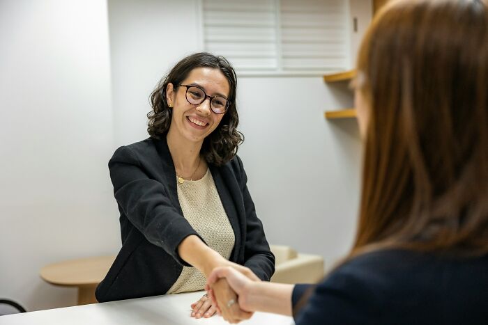 Two women shake hands, one smiling. This represents a fresh start after someone rage quit their job.