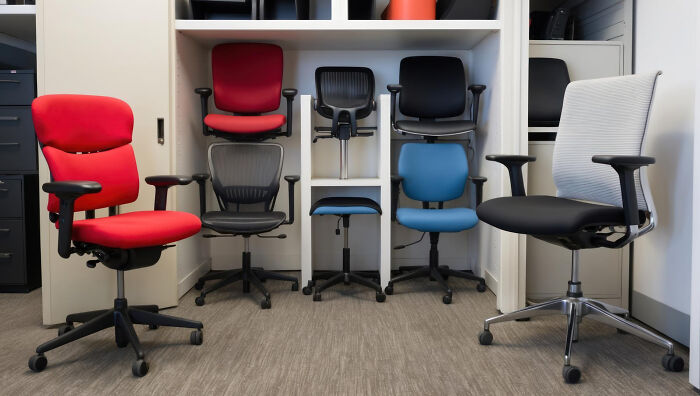 A collection of ergonomic office chairs in various colors, symbolizing absurd rules workplaces implement.