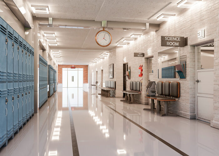 Empty, brightly lit school hallway with lockers, benches, and classroom doors for science and art. Rules workplaces tried to implement.