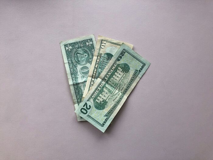 Several US dollar bills fanned out on a plain surface, illustrating the concept of karma in various forms.