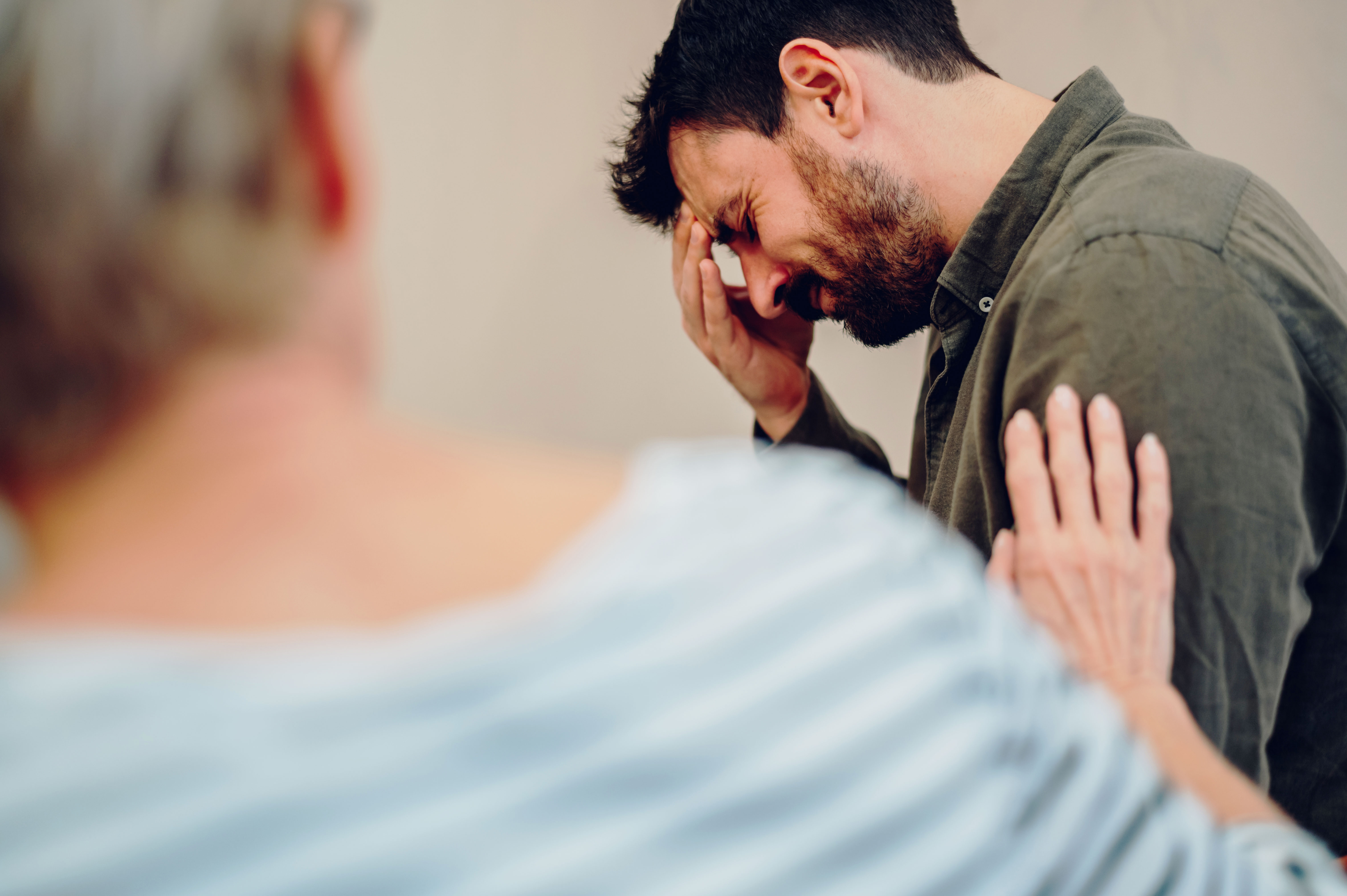 A man, hand to face, expresses distress. A woman's hand gently rests on his shoulder, symbolizing marriage struggles and possible divorce.