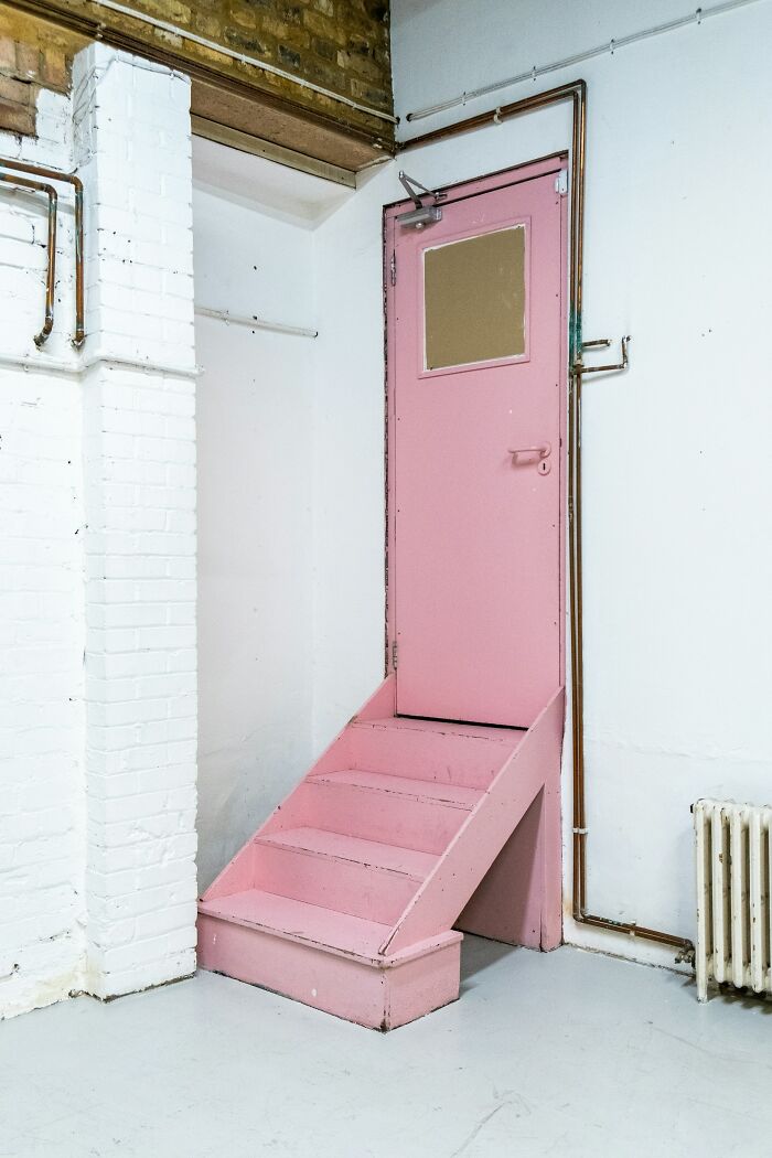 Pink door with small staircase in an industrial space, representing unique and interesting stories about moms.