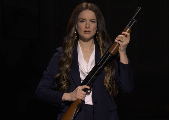 Actress on SNL holding a rifle while portraying a character in a sketch mocking Bryan Noem over scandal backlash.