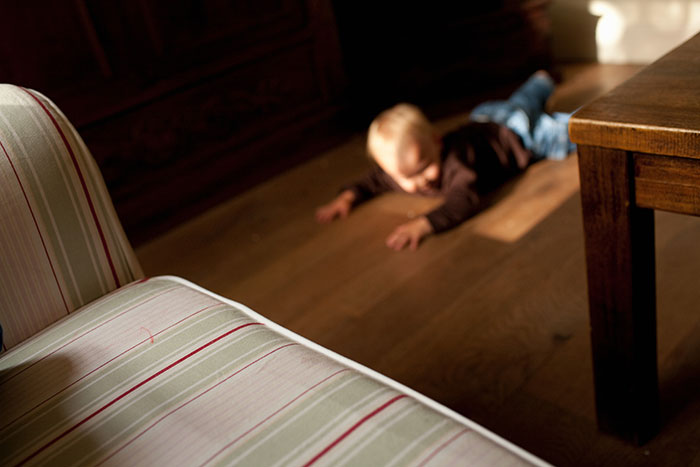 A blurry image of a young child in a brown shirt and blue jeans crawling on a wooden floor, evoking scary experiences.