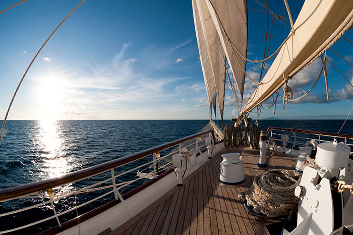 A scenic view from a sailboat deck at sunset, with ocean and blue sky. A reminder of experiences people wish to forget.