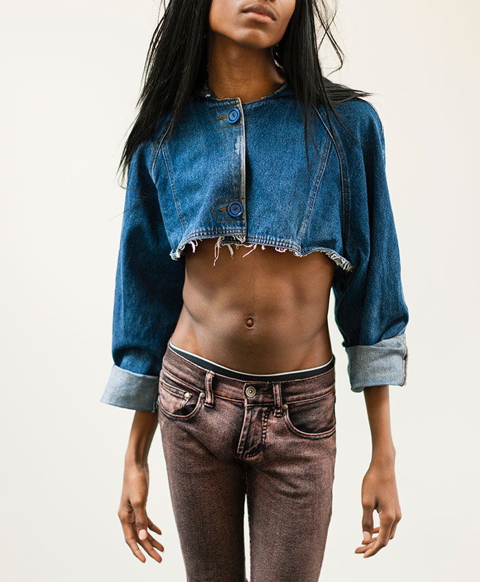 A person with long black hair, wearing a cropped denim jacket and dark jeans, depicting a scary experience.