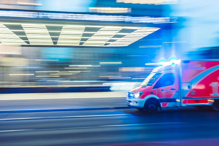 An ambulance with blue lights flashing, speeding down a blurred street, conveying urgent, scary experiences.