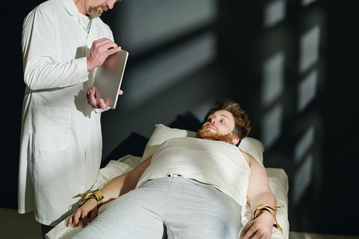 Man in restraints lying on medical bed while doctor in white coat holds a tablet, highlighting unstable ex and scary truth